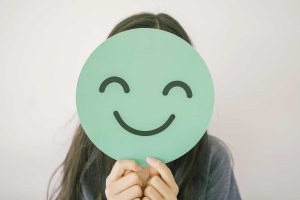 Child holding smiley face infront of them