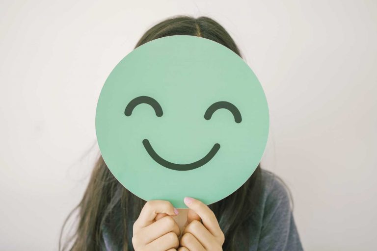 Child holding smiley face infront of them